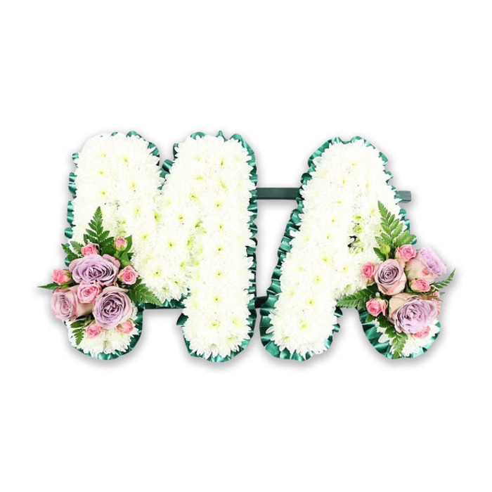 A personalised funeral flower arrangement spelling the letters MA is presented here with the clarity of a studio portrait, evoking a loving farewell to a mother from the Queen's Park community. The tribute is formed from two large capital letters, each one completely blanketed in crisp white chrysanthemums. Every bloom is tightly set against its neighbours, creating a plush, cushion-like texture that looks soft yet substantial, as if it would gently support a resting hand. The petals are finely layered and slightly curved, catching the light in a way that adds delicate shadows and depth to the overall design. Surrounding both letters is a vividly rich green border, likely a pleated satin ribbon or a carefully constructed edging of foliage, which traces every curve and corner of the M and the peaked opening of the A. This border gives the letters sharp definition and brings a touch of refined formality to the tribute, while also evoking the leafy calm of nearby Queen's Park on a quiet afternoon. At the base of the left stem of the M and the lower right of the A, mirrored floral clusters introduce a soft, romantic palette. You can imagine pastel pink roses and gentle lilac roses nestled together, their velvety petals opening in layered swirls, joined by smaller pink spray roses that add intricate detail and texture. Light, feathery fronds of fern and a sprinkling of foliage peek through the blooms, adding movement and a hint of woodland freshness. The entire arrangement is photographed against a smooth white background, free from distractions, so that all attention rests on the letters and their symbolism. This MA tribute feels both intimate and dignified, perfectly suited for a funeral service in a chapel near Salusbury Road, a ceremony by Kensal Green, or a memorial where family and friends gather to honour the enduring presence of a beloved mum in their lives.