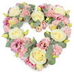 A full, heart-shaped floral wreath is captured against a bright white background, its soft pinks, creams, and greens blending into a tender expression of sympathy that feels right for a farewell near Queen's Park or Kensal Rise. The heart is completely filled with blooms, creating a plush, rounded form that appears gentle and embracing. Creamy yellow and ivory roses serve as the main focal flowers, their spiralling centers and smooth, velvety petals suggesting purity, affection, and quiet strength. Between these roses, pastel pink carnations unfurl in frilled layers, their textured petals overlapping to form a soft, cushion-like effect that underlines the heart's emotional warmth. Scattered throughout, deeper magenta and mauve lisianthus introduce subtle depth, their open, cup-shaped flowers and lightly wavy edges bringing an almost poetic sadness and a sense of layered memories. Weaving through the design are stems of silvery-green eucalyptus, their rounded leaves adding cool, misty tones that gently frame the heart and give the arrangement a natural, soothing aroma. Tiny yellowish-green buds can be seen nestled amongst the larger flowers, hinting at new blossoms just about to open and reinforcing the freshness of the tribute. The overall impression is serene, loving, and respectful, making this heart wreath a meaningful choice for funeral flowers, memorial tributes, or condolence gestures delivered to local chapels, homes, or gathering places around Queen's Park. It visually conveys remembrance, support, and an enduring bond with the person being honoured.